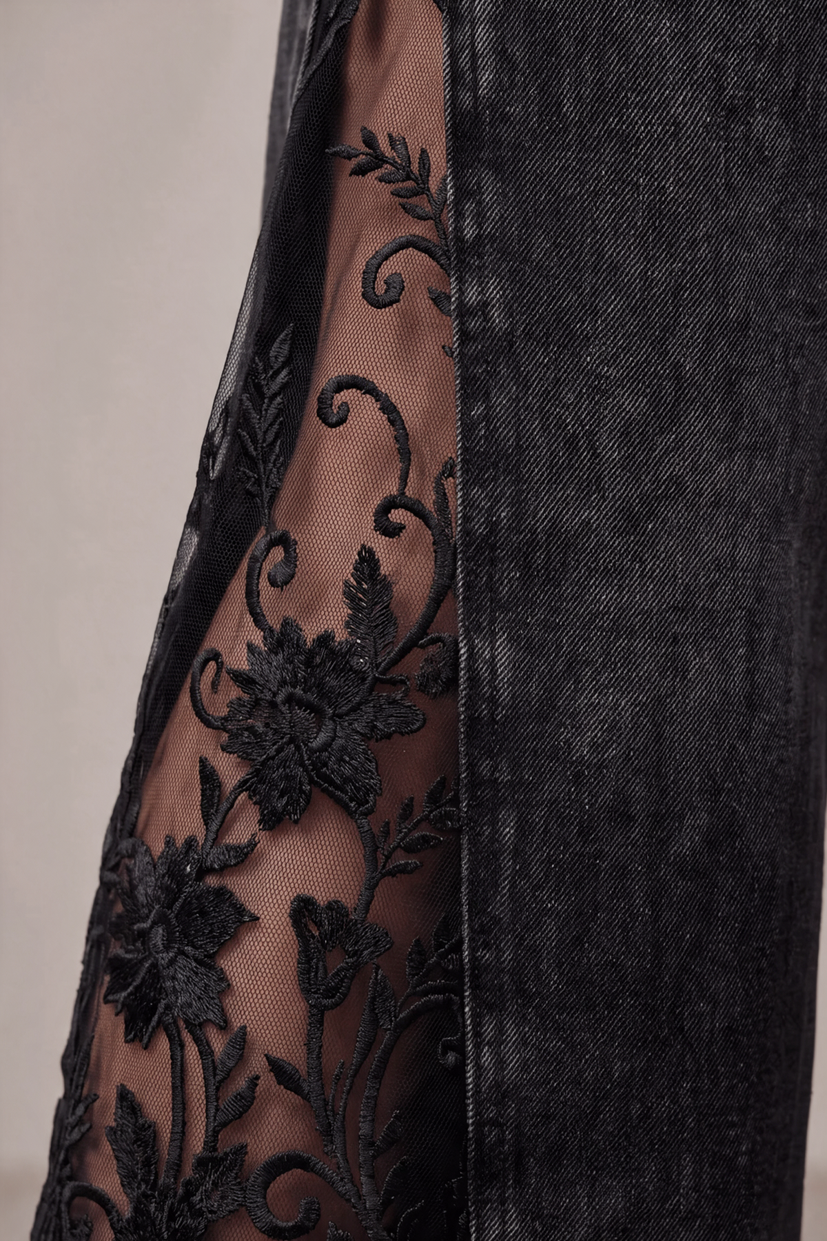Detail of floral lace embroidery on black denim